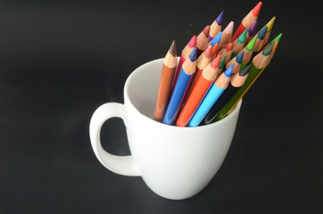 color pencils on a white mug and dark background, colorful, pattern
