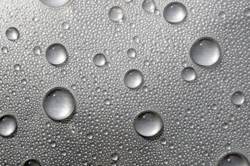 Surface tension. Water drops on the surface covered with foil.