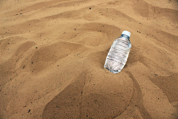 Fototapeta na wymiar Plastic water bottle alone in the sand.