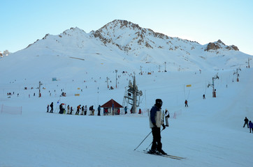 Man skiing in the Andes mountains with a line of lifts in the background