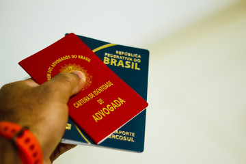 Hand holds identification document of lawyer from Brazil. Carteira da OAB (Ordem dos Advogados do Brasil) e o New Passporte of the República Federativa do Brasil - Mercosur Passport