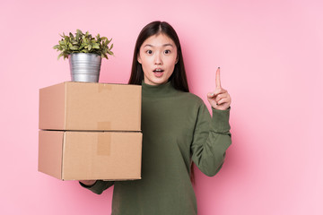 Young chinese woman holding boxes isolated having some great idea, concept of creativity.