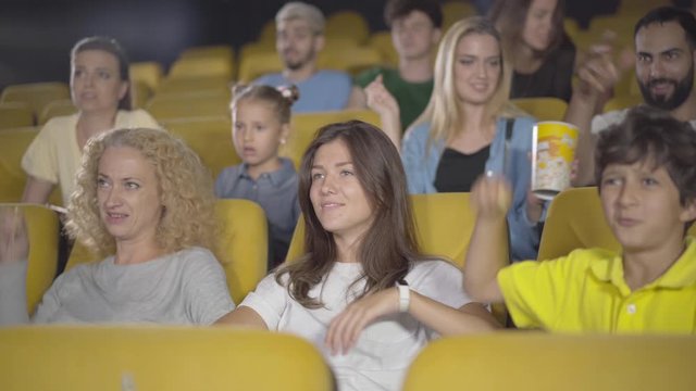 Group of people throwing popcorn in cinema. Portrait of angry film-lovers dissatisfied with film. Men and women of different ethnicities expressing negative emotions in movie theatre.