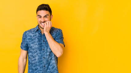Young caucasian man isolated on yellow bakground biting fingernails, nervous and very anxious.