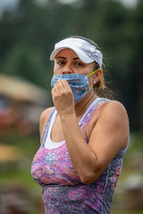 hispanic mexican woman portrait outdoor touching improper used mouth cover as protection from covid...