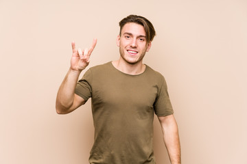 Young caucasian man posing isolated showing a horns gesture as a revolution concept.