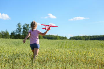 child playing with toy airplane glider in the field