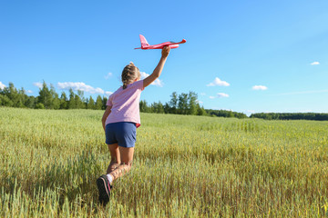 Fototapeta premium child playing with toy airplane glider in the field