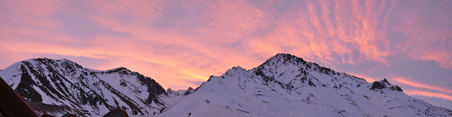 colorful dusk with light clouds and snowy mountains in the foreground