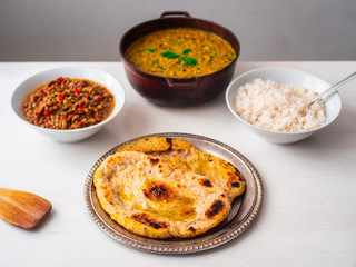 Vegetarian Vegan Indian Buffet of Chick Pea and Spinach Curry, White Rice, Lentil Dhal Stew and Naan Breads in Various Pots and Bowls on a White Background