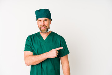 Surgeon senior man isolated on white background smiling and pointing aside, showing something at blank space.