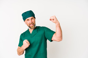 Surgeon senior man isolated on white background raising fist after a victory, winner concept.