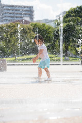 広場の噴水で水遊びする子供