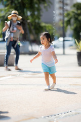 広場の噴水で水遊びする子供