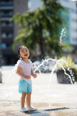 広場の噴水で水遊びする子供