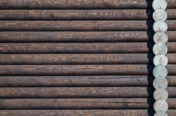 Wooden wall assembled of beams or logs. Dark brown log wall