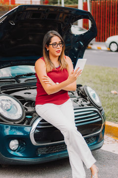 Chica mexicana latina con problemas mec&aacute;nicos usa tableta para arreglar carro pida ayuda