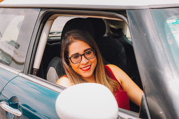 Mujer joven mexicana latina sonríe en pease en auto en dia soleado 