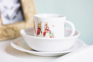 Tea cup with bunny illustration sitting inside white bowl