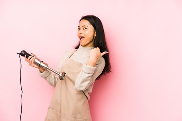 Young chinese woman holding a mixer isolated raising fist after a victory, winner concept.