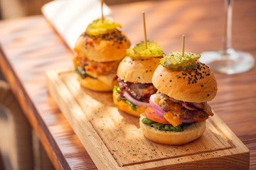 Small grilled burgers served to share on rustic table