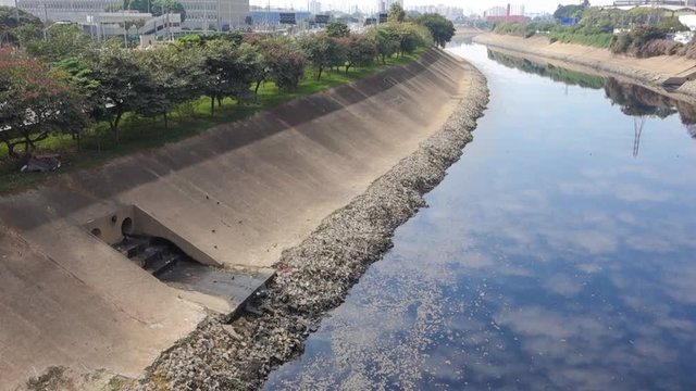 dark waters of the polluted Tiete river flowing. reflecting the sky. Sao Paulo, Brazil