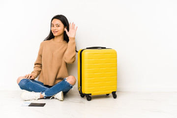 Young chinese traveler woman sittting on the floor with a suitcase isolated smiling cheerful showing number five with fingers.