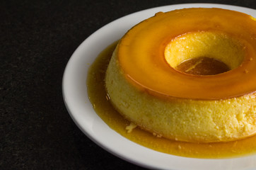 Traditional Brazilian dessert, milk pudding on dark background.