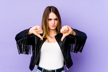 Young caucasian woman isolated on purple background showing a dislike gesture, thumbs down....