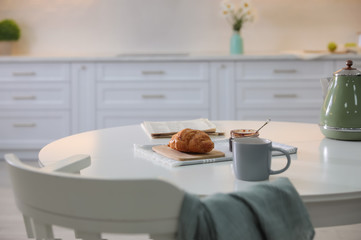 Fototapeta na wymiar Delicious breakfast with fresh croissant and cup of hot drink in kitchen
