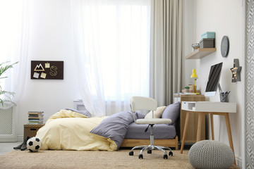 Stylish teenager's room interior with comfortable bed and workplace