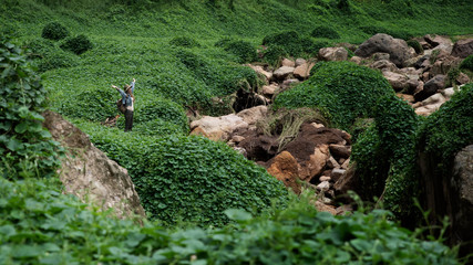 Woman traveler in hat and backpack raised her hands up on a background 