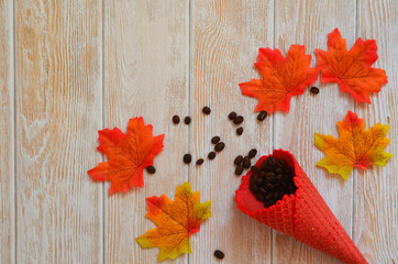 Autumn background with space for text waffle cones with coffee beans and autumn maple leaves flat lay top view