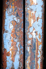 Abstract view of chipped lead paint on badly rusted metal surface; blue, orange, and red colors featured