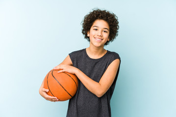 Kid boy playing basketball isolated on blue background laughing and having fun.