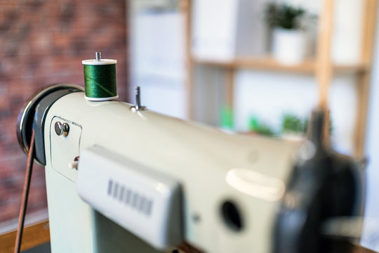 Composition of professional metal sewing machine and square textile for masks with leaves and fruits pattern near sharp scissors in atelier