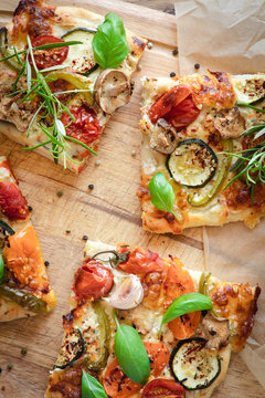From above of palatable vegetarian pizza with cherry tomatoes and mushrooms garnished with fresh basil and rosemary