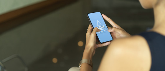 Female hands using mock up smartphone while relaxed sitting in cafe