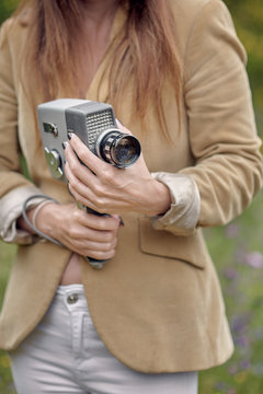 Crop photographer walking in park with vintage video camera