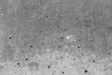 Texture of an aged and weathered grey concrete exterior wall. Plenty of holes around the surface. Conctruction and materials