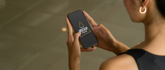 Female hands using mock up smartphone while standing in office room