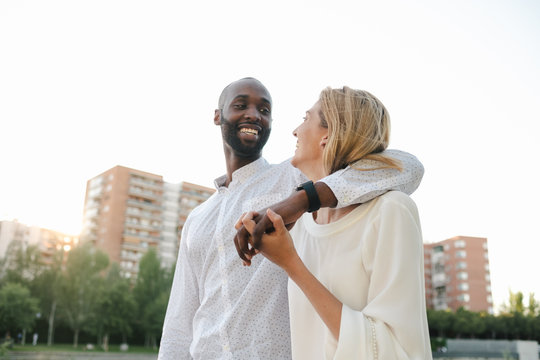 Content black boyfriend and smiling girlfriend while bonding sensually and cuddling together in daytime