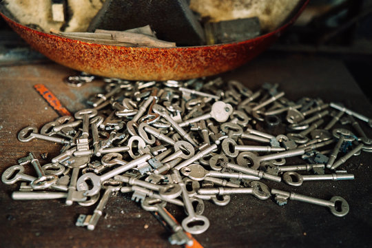 Heap of various metal keys placed on weathered table in old workshop