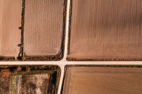 From above aerial view of crossroads going through agricultural field in rural area in summer day