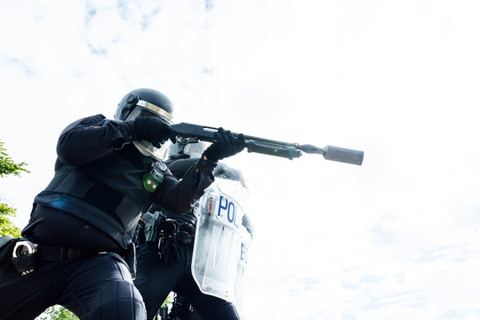 Low angle of swat soldiers in protective uniforms and medical masks armed with assault rifle and riot shield and ready for fight