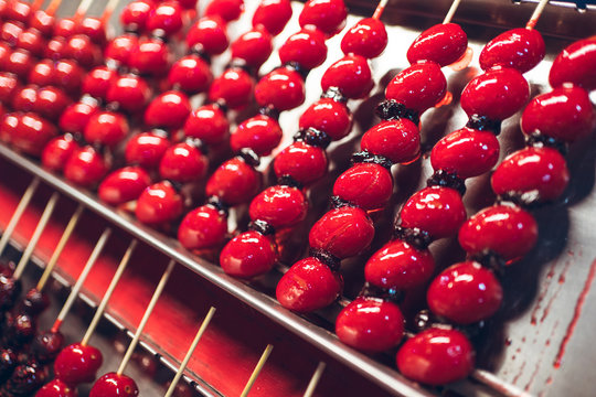 Sugar coated cherry tomatoes on wooden sticks placed in rows on metal counter in Zhubei Night Market