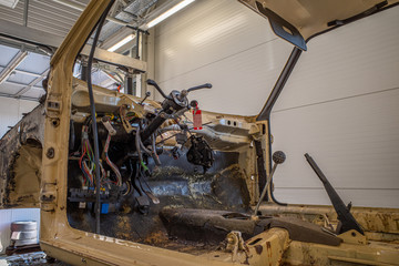 in an auto repair shop there is a stripped-down old car without a steering wheel