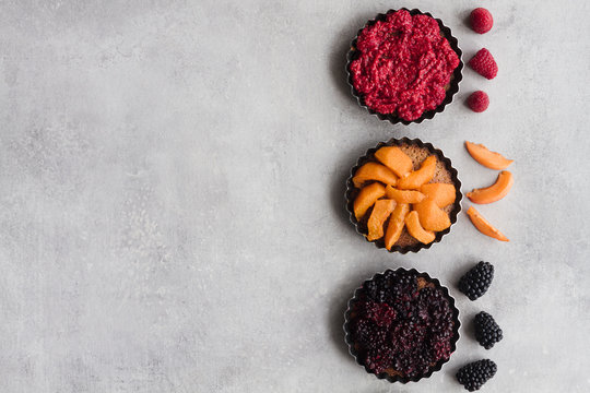 Top view of palatable pies with various ripe fruits and berries arranged in line on table