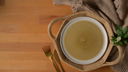 wooden kitchen table with mock up plate on wicker tray, silverware, copy space, tablecloth and decoration