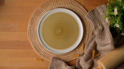 wooden kitchen table with mock up plate on placemat, kitchen tools, tablecloth and decoration